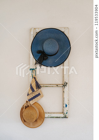 Old Summer straw hats hanging on rustic white wall 119533904