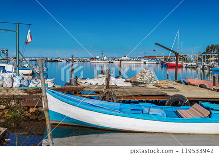 Serene harbor scene with boats docked by the pier, clear blue sky, calm waters 119533942