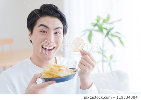 一個男人微笑著吃薯片 一個男人微笑著吃薯片 119534394