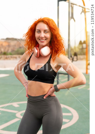 Happy sporty woman in activewear standing with 119534714