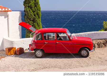 Red retro car with open trunk and luggage against the background of the sea in Cadaques Red retro car with open trunk and luggage against the background of the sea in Cadaques 119535096