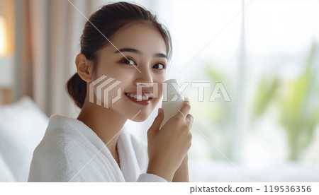 Attractive Asian Woman In Bathrobe Admiring Skin After Applying Lotion, Feeling Happy And Proud In Bedroom. Healthy Beauty Treatment. 119536356