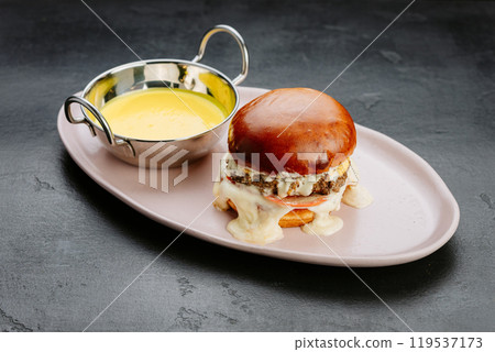 Juicy burger with melted cheese, tomato, and creamy sauce for the ultimate indulgent meal experience 119537173