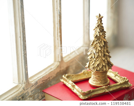 Old books and a Christmas tree on a retro windowsill 119538481