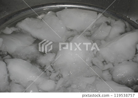 Cloudy ice in a stainless steel bowl in the sink 119538757