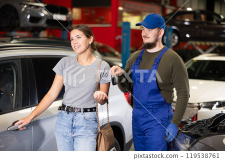 Young male mechanic giving car keys to woman client 119538761