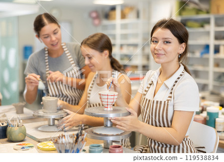 Girl student paints ceramic cup in workshop Girl student paints ceramic cup in workshop 119538834