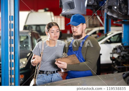 Girl explains the problems of her car to mechanic. Man writes data on paper 119538835