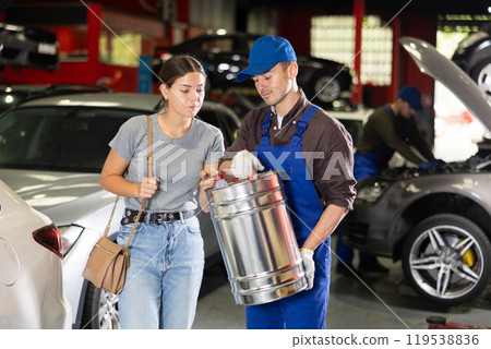 Young male mechanic giving gasoline to female customer Young male mechanic giving gasoline to female customer 119538836