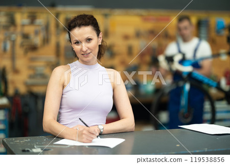 Woman in bicycle repair service signing document Woman in bicycle repair service signing document 119538856