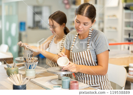 Girls perform work on molding blanks from raw clay and painting staining them Girls perform work on molding blanks from raw clay and painting staining them 119538889