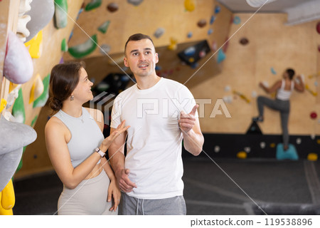 Girl gym coach and teen client standing in fitness room discussing possible options climbing 119538896