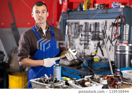 Portrait of professional auto mechanic in uniform with tools in his hands in car service center 119538944
