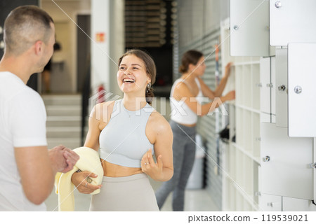 Smiling girl talking with friend by storage lockers in bouldering gym Smiling girl talking with friend by storage lockers in bouldering gym 119539021