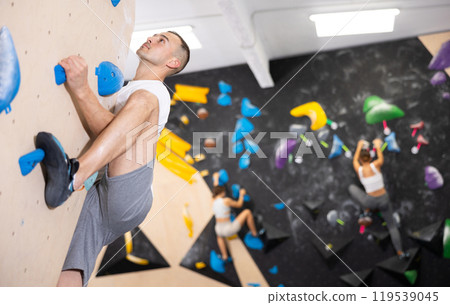 Young man practicing rock climbing on climbing wall Young man practicing rock climbing on climbing wall 119539045