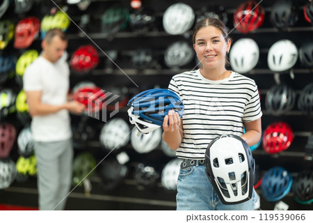 Young woman choosing bicycle helmet in store Young woman choosing bicycle helmet in store 119539066