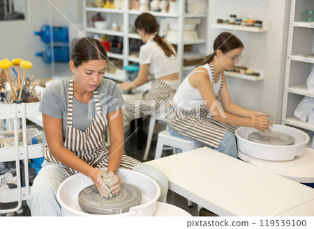 Woman teacher and students make products on potter's wheel 119539100