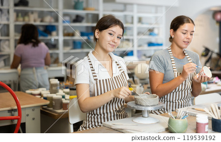 Two young women sculpt and paint ceramics 119539192