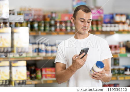 Young man scanning qr code for mayonnaise Young man scanning qr code for mayonnaise 119539220