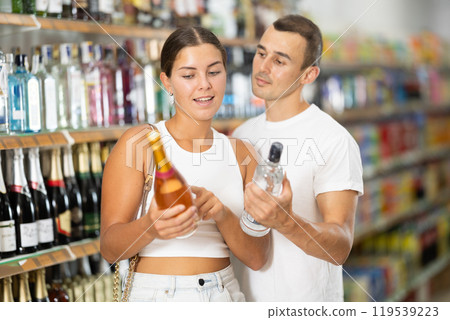 Married couple chooses alcoholic drinks in supermarket - vodka, champagne or whiskey 119539223