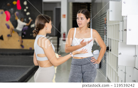 Girl enjoying chat with female friend by lockers at climbing gym Girl enjoying chat with female friend by lockers at climbing gym 119539242