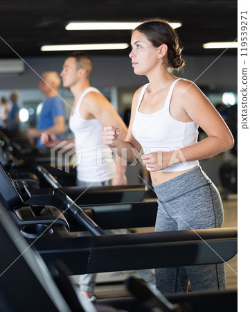 Girl walk on treadmill in gym. Healthy lifestyle, extensive training Girl walk on treadmill in gym. Healthy lifestyle, extensive training 119539271