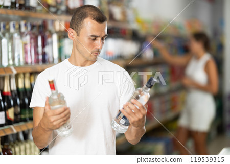 Male shopper selects wodka in produce section of supermarket 119539315