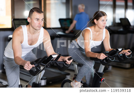 Young man exercising on exercise bike Young man exercising on exercise bike 119539318