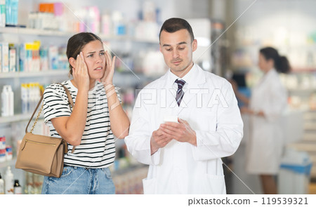 Male pharmacist advises headache medicine to woman Male pharmacist advises headache medicine to woman 119539321
