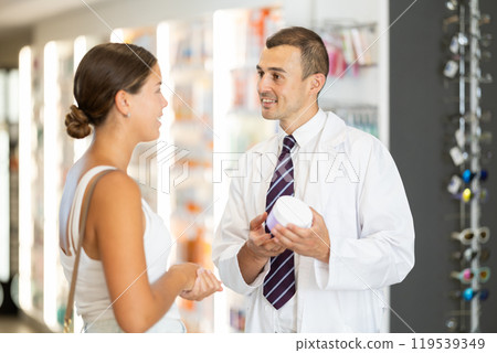 Male pharmacist consulting young girl about cosmetic cream 119539349