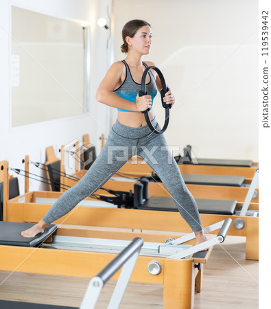 Girl restores her health with the help of gymnastic ring during Pilates classes 119539442