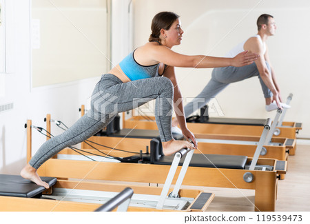 Girl practicing exercises on Pilates reformer during rehabilitation session 119539473