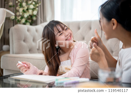 A young, adorable and happy Asian girl is enjoying playtime with her mom at home, coloring together. A young, adorable and happy Asian girl is enjoying playtime with her mom at home, coloring together. 119540117