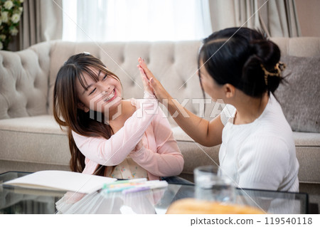 A young, adorable Asian girl is enjoying playtime with her mom at home, giving each other high five. A young, adorable Asian girl is enjoying playtime with her mom at home, giving each other high five. 119540118