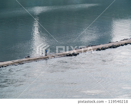 A man walking on the waterway dam build in the middle of Jialing River A man walking on the waterway dam build in the middle of Jialing River 119540218