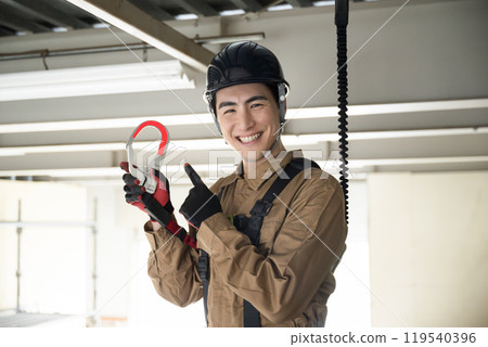 一名佩戴安全帶的現場工作人員擺出姿勢：“高空作業注意安全！” 119540396