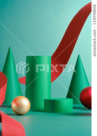 With a teal backdrop, the image showcases a Christmas theme, consisting of a gold sphere, a red sphere, and a green cone with green cylinder podiums for product displays connected by a red ribbon. With a teal backdrop, the image showcases a Christmas theme, consisting of a gold sphere, a red sphere, and a green cone with green cylinder podiums for product displays connected by a red ribbon. 119540608