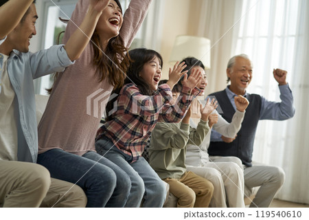 three generation asian family watching soccer game telecast on tv together at home 119540610
