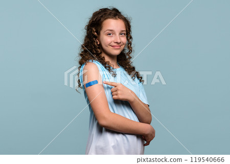Smiling girl pointing at bandage on vaccinated arm. Smiling girl pointing at bandage on vaccinated arm. 119540666