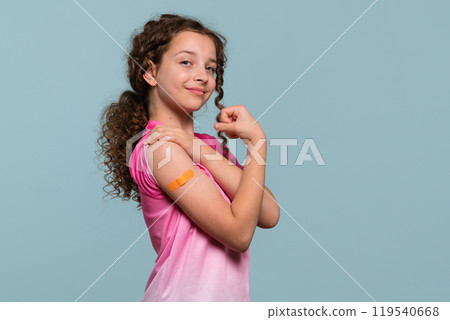 Girl flexing arm with orange bandage after receiving vaccine shot 119540668