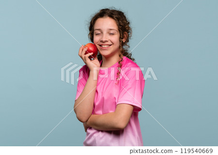 Girl with eyes closed, holding an apple. 119540669