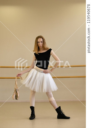 Ballerina posing with pointe shoes in hand Ballerina posing with pointe shoes in hand 119540678