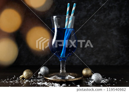 Blue cocktail in glass, christmas balls and snow on dark background 119540982