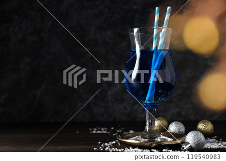 Blue cocktail in glass, christmas balls and snow on dark background, space for text 119540983