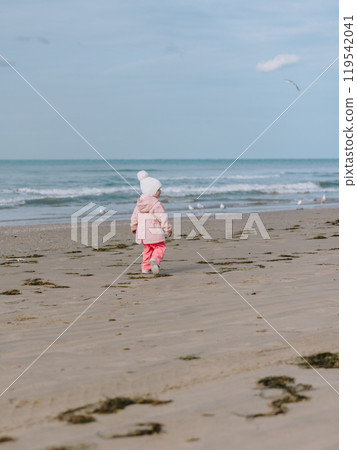 Little child girl walk on ocean coastline. Winter concept. Little child girl walk on ocean coastline. Winter concept. 119542041