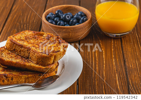 French toast on a white plate with blueberries and orange juice for breakfast 119542342