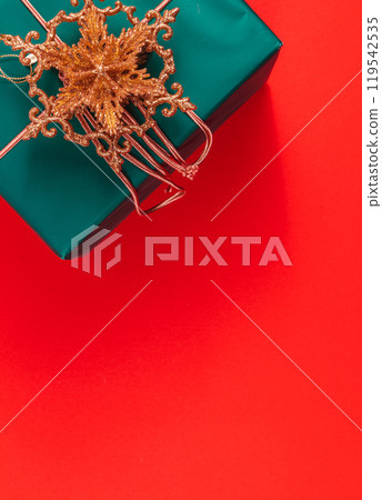 Dark green Christmas gift box with gold star decoration on red background 119542535