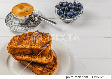 French toast on a white plate with blueberries and coffee for breakfast French toast on a white plate with blueberries and coffee for breakfast 119542580