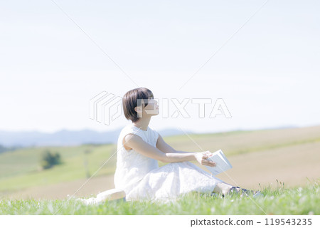 Young woman reading a book in the grass Young woman reading a book in the grass 119543235