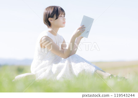 Young woman reading a book in the grass 119543244